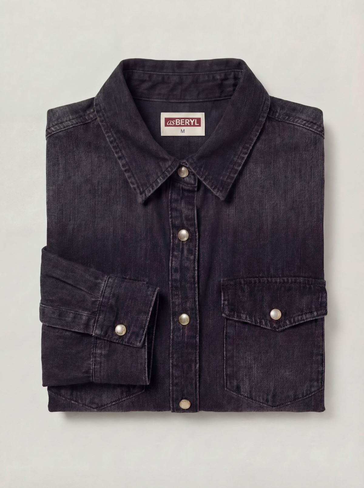 Folded dark denim shirt with visible brand label on a light gray background